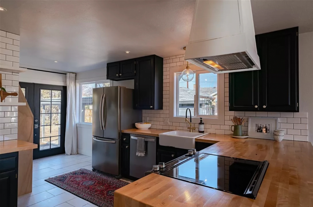 kitchen remodel with wood finish countertops and black and white themed kitchen cabinets.